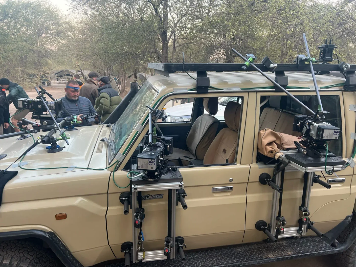 Crew preparing a 4x4 rigged with multiple cameras mounted on the bonnet, doors and roof rack.